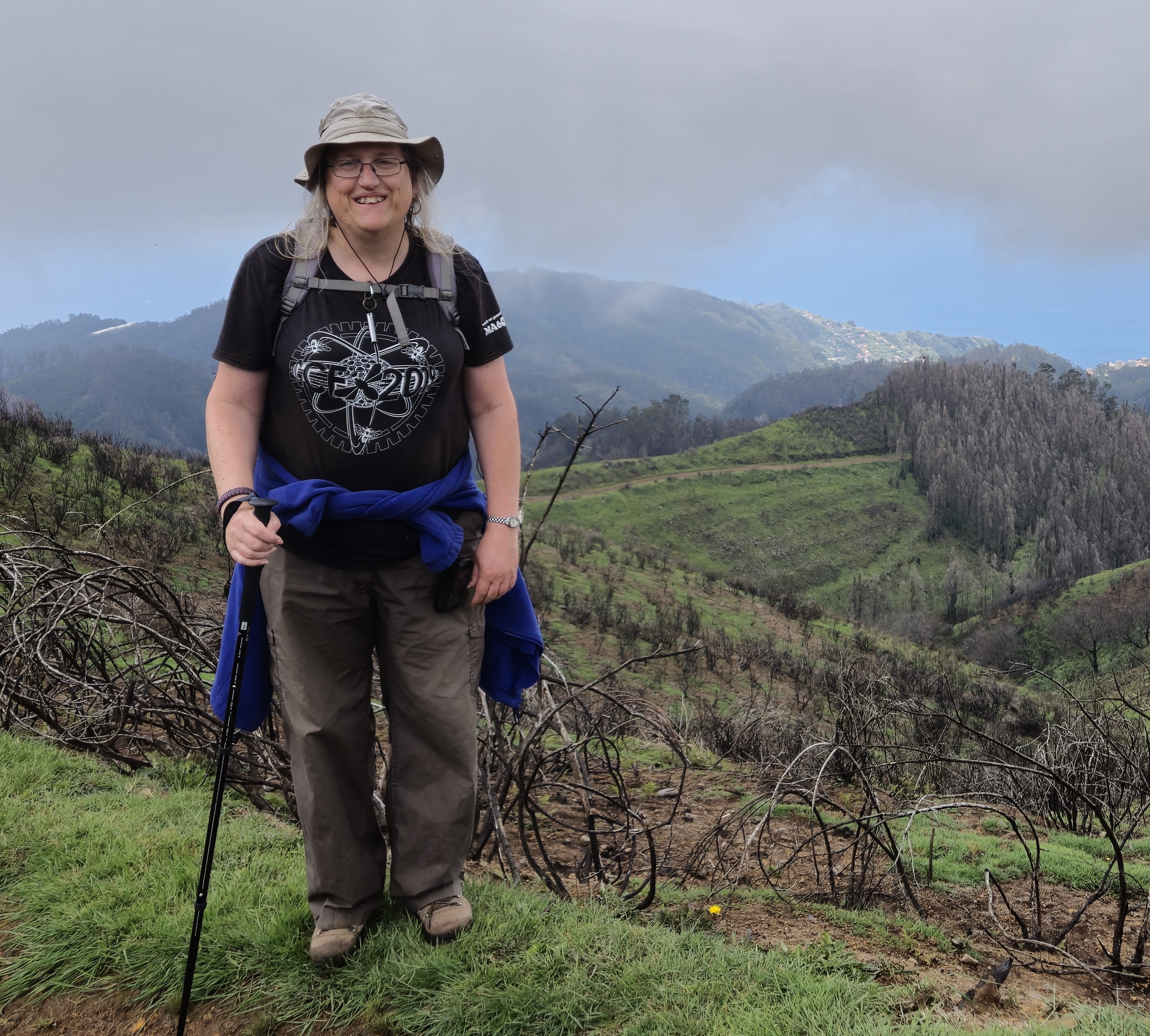 Helen has her coat tied round her waist and is posing with some hills in the background